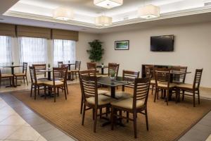 a dining room with tables and chairs and a flat screen tv at Sleep Inn & Suites Harbour Pointe Midlothian in Brandermill