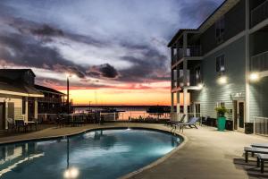 a swimming pool in front of a building with a sunset at Marina Bay Hotel & Suites, Ascend Hotel Collection in Chincoteague