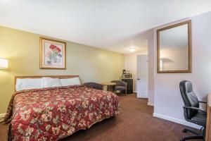 Habitación de hotel con cama y espejo en Rodeway Inn, en Bellows Falls