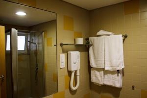 ein Bad mit einer Dusche, einem Spiegel und Handtüchern in der Unterkunft INATEL Oeiras in Oeiras