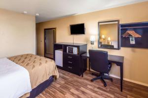 a hotel room with a bed and a desk with a computer at Quality Inn Moses Lake in Moses Lake