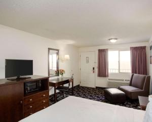 um quarto de hotel com uma cama e uma secretária com uma televisão em MorningGlory Inn & Suites em Bellingham
