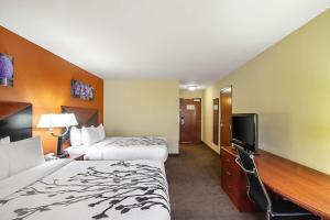 a hotel room with two beds and a flat screen tv at Sleep Inn & Suites in Madison