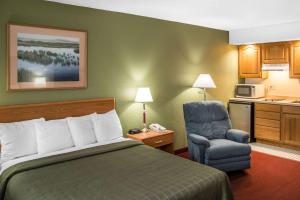 a hotel room with a bed and a chair at Hudson Inn & Suites in Hudson