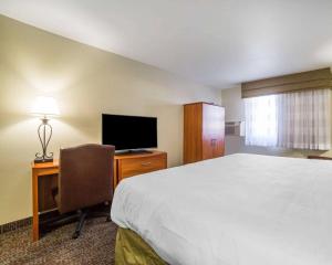 Habitación de hotel con cama y escritorio con TV. en Quality Inn en Gillette