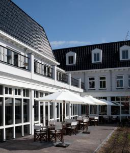 eine Gruppe von Tischen und Sonnenschirmen vor einem Gebäude in der Unterkunft Fletcher Hotel-Restaurant Duinzicht in Ouddorp