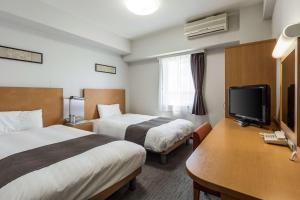 Habitación de hotel con 2 camas y TV de pantalla plana. en Comfort Hotel Central International Airport, en Tokoname