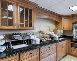 a kitchen with wooden cabinets and a counter top with food at Comfort Suites Airport in Wichita