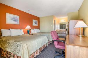 Habitación de hotel con 2 camas, escritorio y silla en Executive Inn Dodge City, KS, en Dodge City