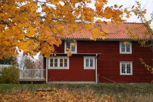 a red house with white windows and a porch at Brännsjötorp in Målilla