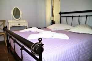 a bedroom with a bed with purple sheets and a mirror at Luxury Stone Villa in Fiskardho