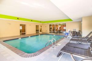 a pool in a hotel room with chairs and tables at Quality Suites in Corbin
