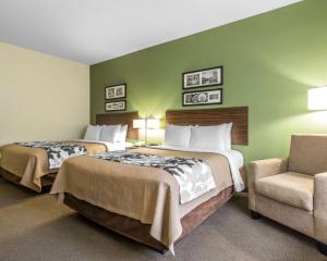 a hotel room with two beds and a chair at Sleep Inn & Suites Middlesboro in Middlesboro