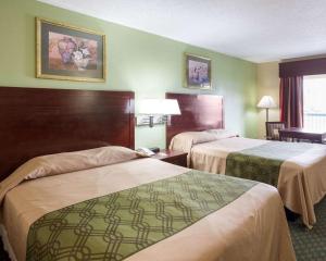 two beds in a hotel room with green walls at Rodeway Inn & Suites in New Orleans