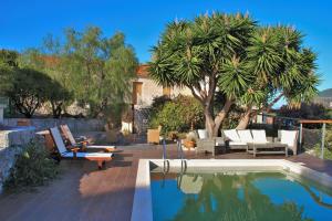 a pool with lounge chairs and a palm tree at Luxury Stone Villa in Fiskardho