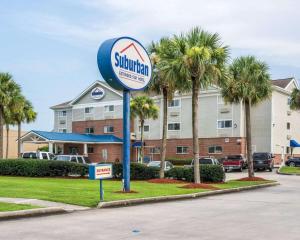 a sign in front of a hotel with palm trees at Suburban Studios Avondale in Avondale