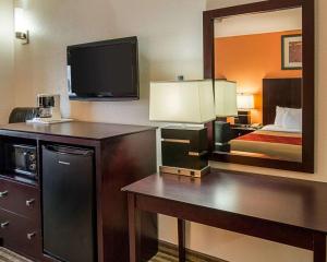 Econo Lodge Inn & Suites Natchitoches في نتشتوشس: غرفة فندقية بسرير ومكتب مع تلفزيون