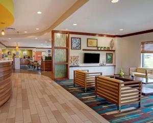 a hotel lobby with benches and a tv and a bar at Comfort Suites Bossier City - Shreveport East in Bossier City