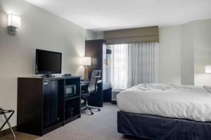 a hotel room with a bed and a desk with a television at Sleep Inn Baton Rouge East I-12 in Baton Rouge