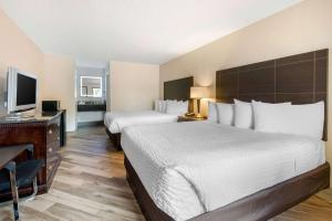 a hotel room with two beds and a desk and a television at Clarion Inn & Suites Kissimmee-Lake Buena Vista South in Kissimmee