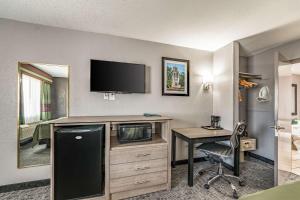 Habitación de hotel con escritorio y TV en la pared en Quality Inn I-10 East near Frost Bank Center, en San Antonio