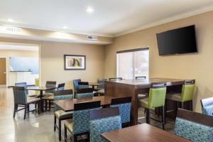 a restaurant with tables and chairs and a flat screen tv at Comfort Inn South Tulsa - Woodland Hills in Tulsa