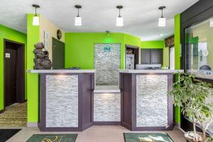uma cozinha com paredes verdes e dois bancos de bar em Quality Inn Grand Rapids Near Downtown em Grand Rapids