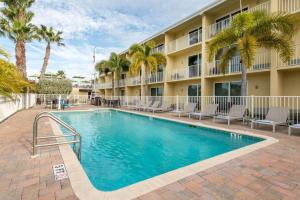 a swimming pool in front of a hotel with palm trees at Treasure Bay Resort & Marina in St Pete Beach