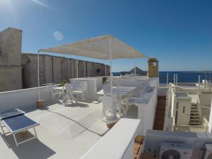 a patio with white chairs and a white umbrella at Corte De Noie Appartamenti Gallipoli in Gallipoli