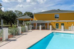 a swimming pool in front of a yellow house at Quality Inn in Kingstree