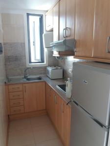 Elle comprend une petite cuisine avec des placards en bois et un réfrigérateur. dans l'établissement APARTAMENTOS BUNGAMERICA n114, à Playa de las Americas
