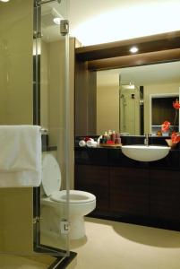 a bathroom with a sink and a toilet and a mirror at The Narathiwas Hotel & Residence Sathorn Bangkok in Bangkok