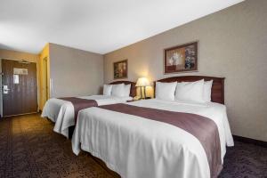 een hotelkamer met twee bedden met witte lakens bij Quality Inn Burlington in Burlington +20 foto's