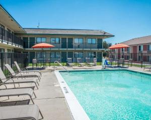 a pool with chairs and umbrellas next to a building at Rodeway Inn Greeley in Evans