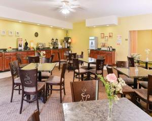 a dining room with tables and chairs and a kitchen at Quality Suites Stratford in Stratford