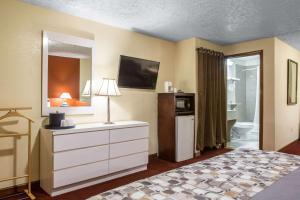 a bedroom with a bed and a dresser and a bathroom at Rodeway Inn & Suites Branford - Guilford in Branford