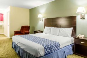 Pokój hotelowy z dużym łóżkiem i krzesłem w obiekcie Rodeway Inn w mieście Groton
