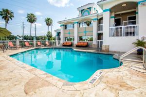 基西米Quality Inn Clermont West Kissimmee的一座带椅子的度假村的游泳池和一座建筑
