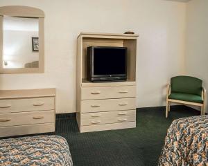 Habitación de hotel con TV y vestidor con cama en Rodeway Inn Gainesville - University Area, en Gainesville