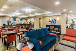 un restaurante con sofá azul, mesas y sillas en Comfort Inn Pensacola - University Area en Pensacola