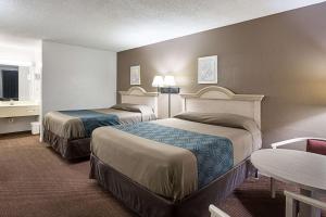 a hotel room with two beds and a table at Rodeway Inn Lake City I-75 in Lake City