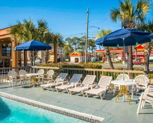 a group of chairs and tables and umbrellas next to a pool at Econo Lodge in Panama City
