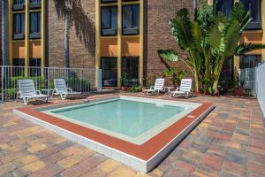 a swimming pool with two chairs and a building at Comfort Inn & Suites Kissimmee by the Parks in Orlando