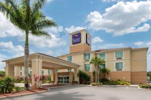 a hotel with a palm tree in front of a building at Sleep Inn & Suites Port Charlotte-Punta Gorda in Port Charlotte