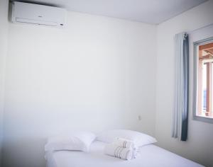 Cama blanca con almohadas blancas y ventana en Pousada Dona Alice, en Florianópolis