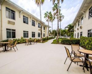 un patio con mesas, sillas y palmeras en Sleep Inn at PGA Village, en Port Saint Lucie