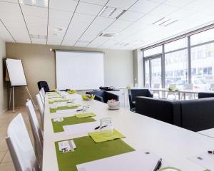 a conference room with a long table with chairs and a whiteboard at Appart hôtel Q7 Lodge Lyon 7 in Lyon