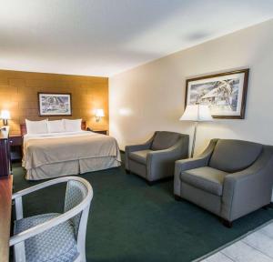 a hotel room with a bed and two chairs at Econo Lodge Cocoa Beach - near the Port in Cocoa Beach