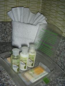 a plastic container with four bottles of moisturizers and a towel at Holiday Inn St. Louis Airport West Earth City, an IHG Hotel in Earth City