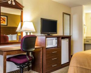 a hotel room with a desk with a television and a bed at Quality Inn & Suites Morrow Atlanta South in Morrow